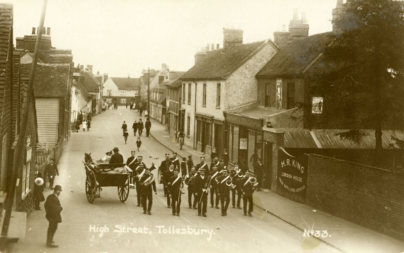  High Street, Tollesbury. Postcard No.33.

Band marching. H.R. King, London House, shop on right. 
Cat1 Tollesbury-->Road Scenes