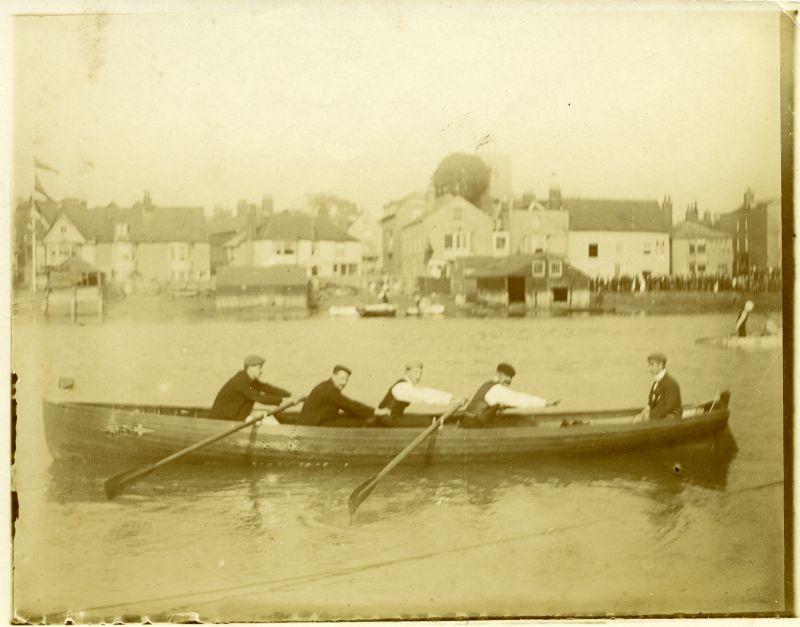  Rowhedge Shipwrights Gig's Crew pose in PHANTOM's gig. 1. G Barnard 2. John Cheek 3. J Theobald 4. F Rose 5. Arthur 'Doc' Springett. circa 1902. Wivenhoe waterfront in the background. 
Cat1 Ships and Boats-->Other Cat2 Places-->Wivenhoe-->Town