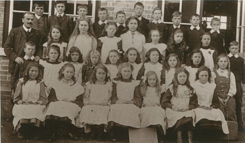  Birch School group I. 1890s. Headmaster Mr Chandler on the left.

Back row L-R 1., 2. Charlie Everitt, 3., 4., 5., 6., 7., 8., 9., 10.

Second from back 1. Mr Chandler, headmaster, 2. Eva Partner, 3. Ida Bond, 4., 5. Beatrice Tosbel [born 1899], 6. Lily Pentney, 7. Ida Polly, 8. Eva French, 9.

Third from back 1., 2., 3. Maud Fisher, 4. Violet Pepper, 5., 6. Nora Tosbel, 7. Meg ...
Cat1 Birch-->School