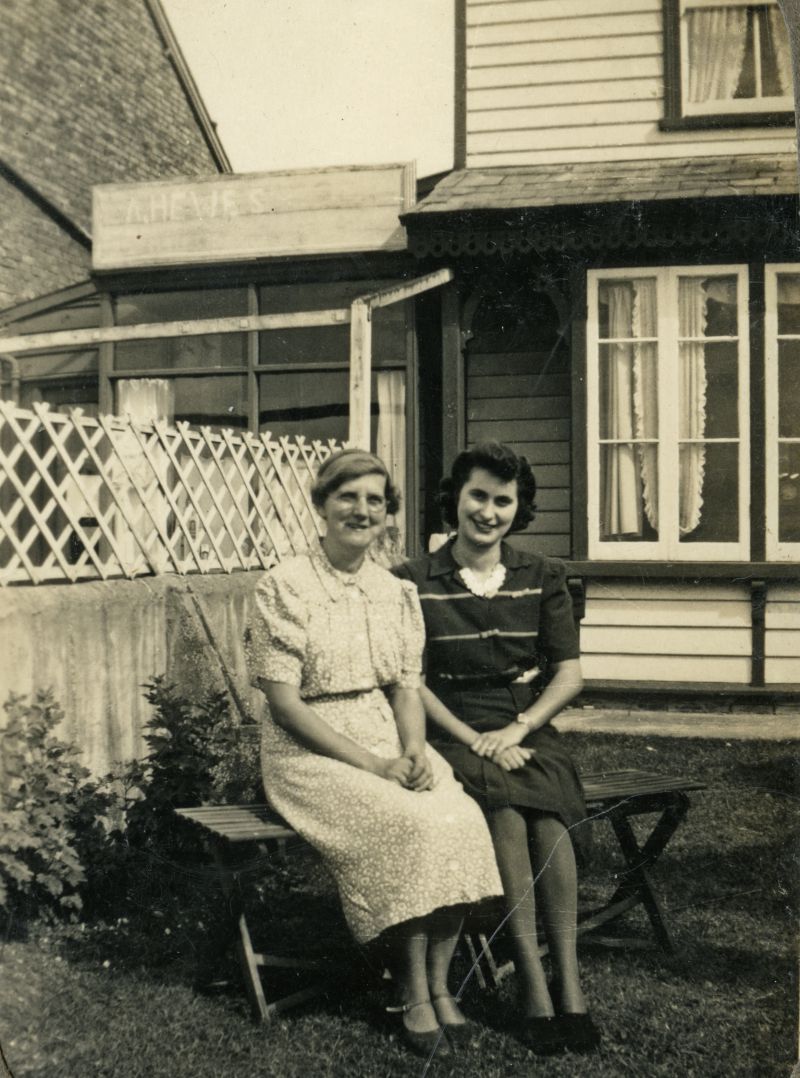 Grace Evelyn Hewes née STOKER and Rita Stoker (Eric Stoker's wife) 

A. Hewes shop on left - it is Blackwater Pearl in 2018.

[Andy Brown]

The house is Fleetview on Coast Road, home of Grace and Sid Stoker. 
Cat1 Families-->Stoker / Brown Cat2 Families-->Hewes Cat3 Mersea-->Shops & Businesses