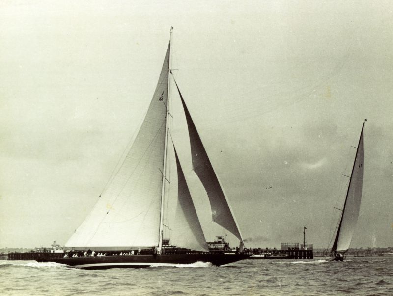  The blue hulled ENDEAVOUR, K4, and the green hulled ASTRA, K2, prepare for the start at Southend on Sea regatta in 1934. Both have a single reef in the mainsail as the fresh wind will harden when they race seawards into the more open waters of the estuary of the Thames. An excursion paddle steamer lies alongside the pier end embarking trippers for a day's outing, enhanced by the excitement of the ...
Cat1 Yachts and yachting-->Sail-->Larger Cat2 Places-->Southend