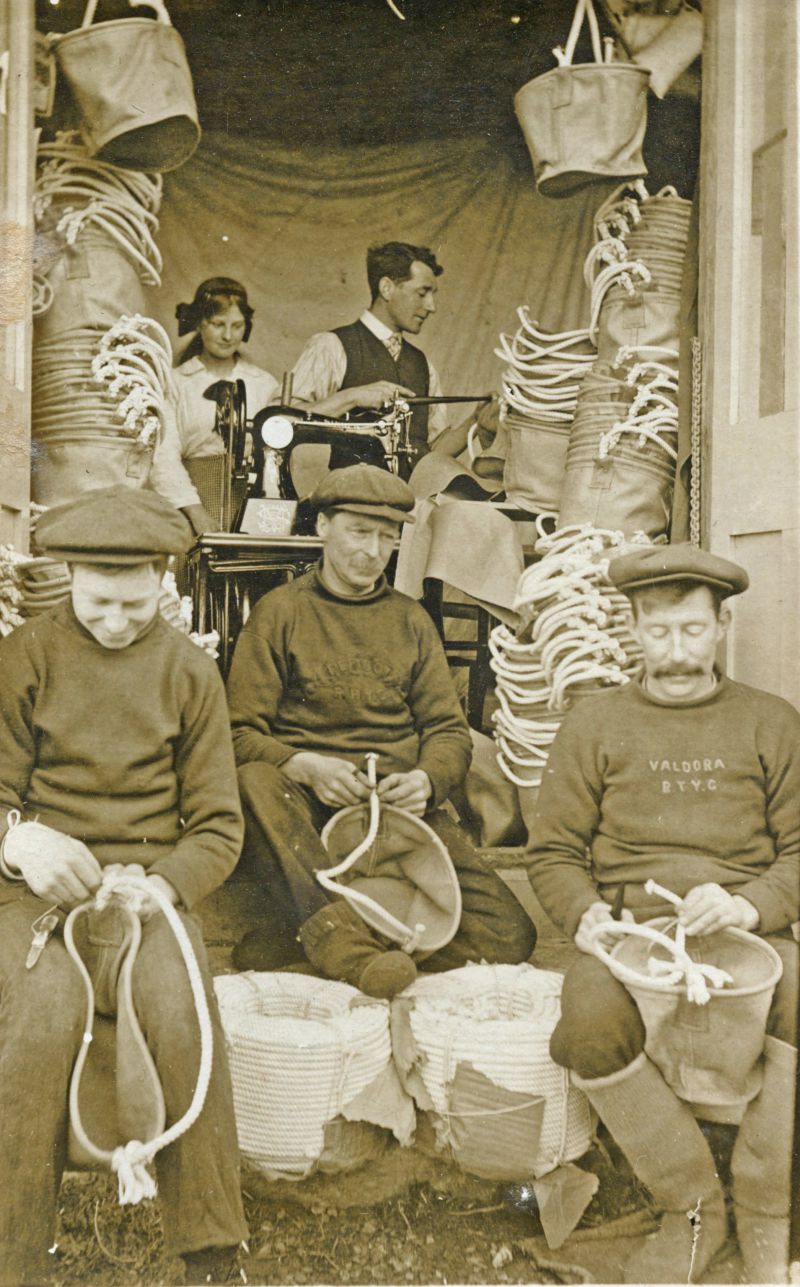  Making rope handles for canvas buckets Back : Cuddy Hewes and Herbert Welham Front : Freddie French, John French and Fred Hewes.

Gowen & Co., Mersea. VALDORA on jersey. 
Cat1 Families-->Hewes Cat2 Ship and boat building, sailmaking Cat3 Families-->French