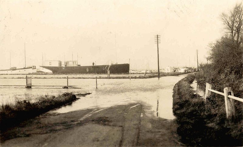  Coast Road, houseboat ERYCINA. High tide across the road.

ERYCINA yawl built 1882 Fife & Son, Fairlie, 72 tons, Official No. 85939. Registered Glasgow, owner P.F.G. Lord [Lloyds Yacht Register 1900] 
Cat1 Mersea-->Coast Road Cat2 Mersea-->Houseboats Cat3 Yachts and yachting-->Sail-->Larger