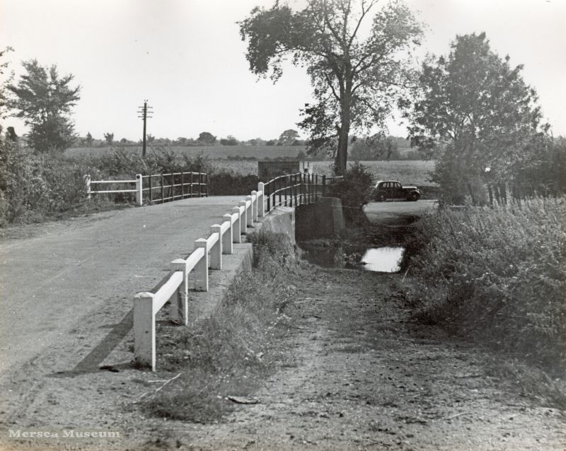  River Colne down to the Sea by Douglas Went. Photograph 10.

Chitts Hill / Newbridge, West Bergholt. Beyond the bridge, a pillbox and Douglas Went's car. 
Cat1 Places-->Colne