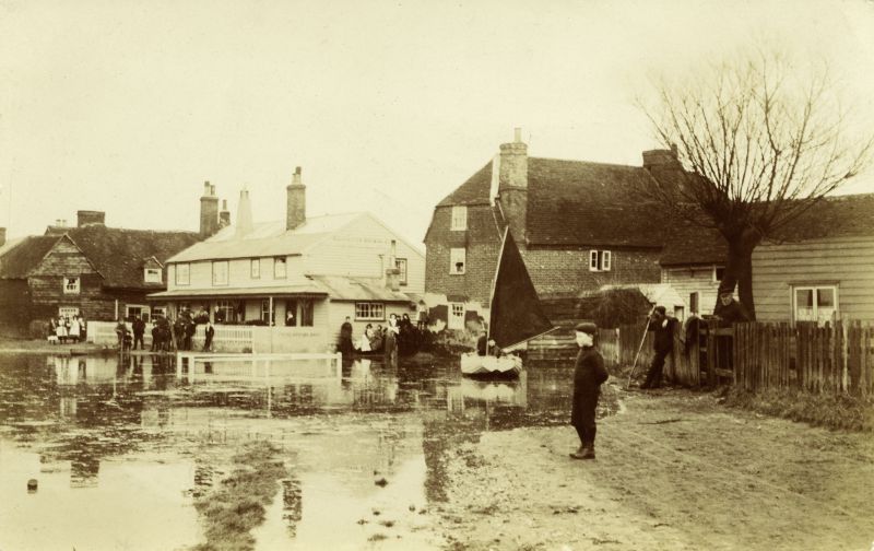  High tide at the Old City - 'old' Victory and Cornerways to the right of it. 

The white railings this side of the old Victory are where the Bumby Ditch came out, after going under the road.

BJ35_029 No.1 original posted 15 Oct 1906

Photograph by Cleghorn. Also published by Mersea Museum as a postcard. 
Cat1 Mersea-->Old City & the Hard