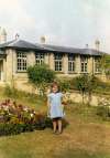  Susan Millatt in the garden of School House, Birch, with the school in the background.
 Photo 130E TBM  PBA_130_EEE