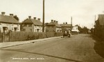  Barfield Road with the 'old' council houses on the left. Beyond them is Bamborough's, chemists - there is still a chemist on the site. The big shed on the right is Clifford White's coal shed. Motor cycle with sidecar. Postcard postmarked 18 Jan 1944, addressed to Miss Smith, Upland House, West Mersea. The photograph probably dates to 1935 or before - the distant bus looks to date from before the Eastern National takeovers of that year.  MMC_P756_A